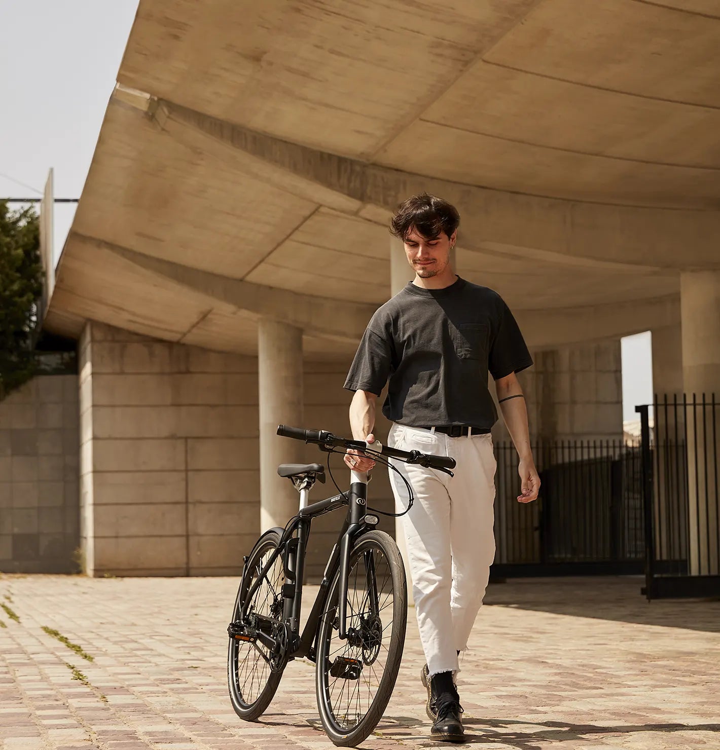 Cycliste marchant à côté de son vélo Bastille en le tirant par sa potence, sans le porter.