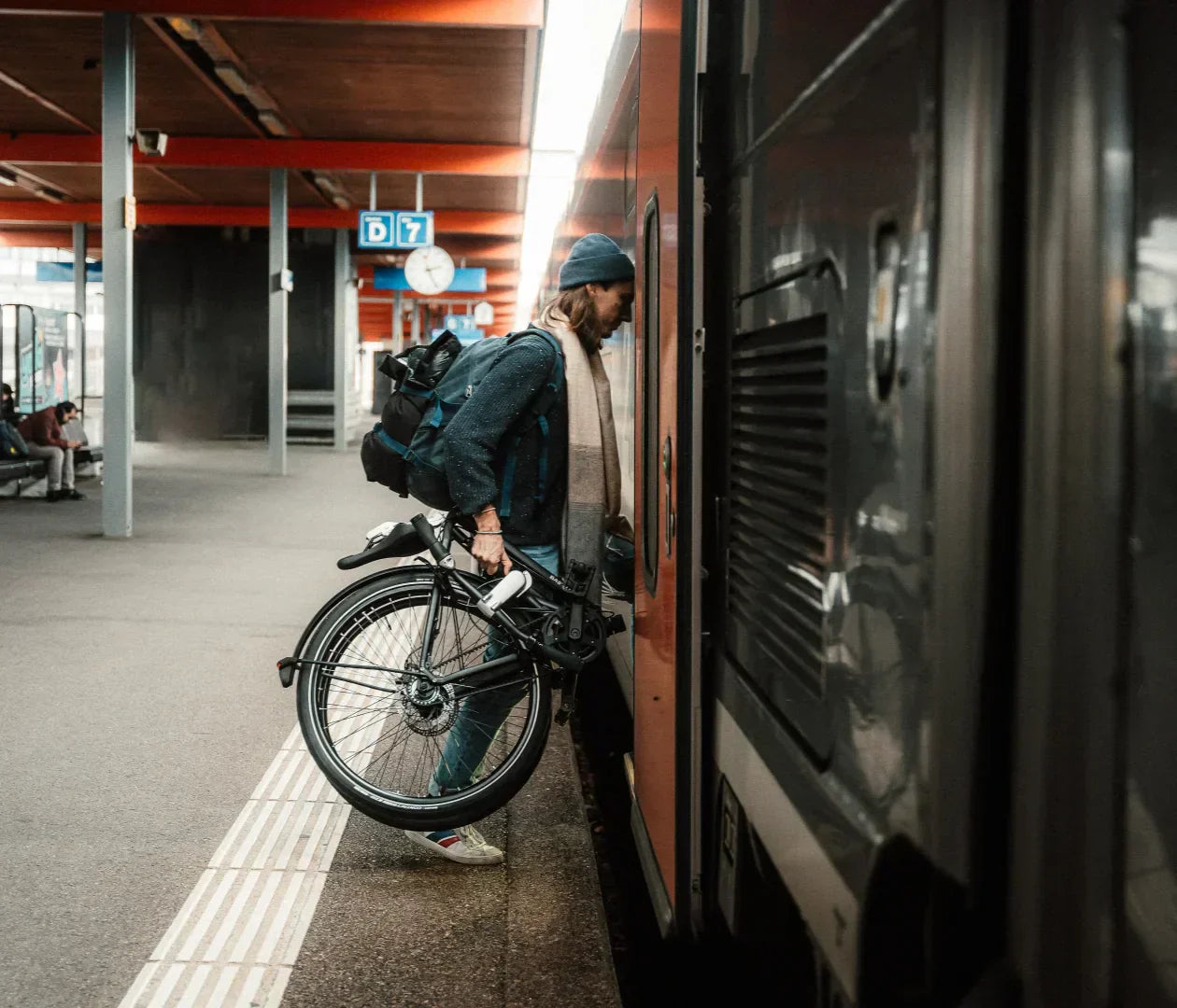 Un homme entre dans un train avec son vélo plié.