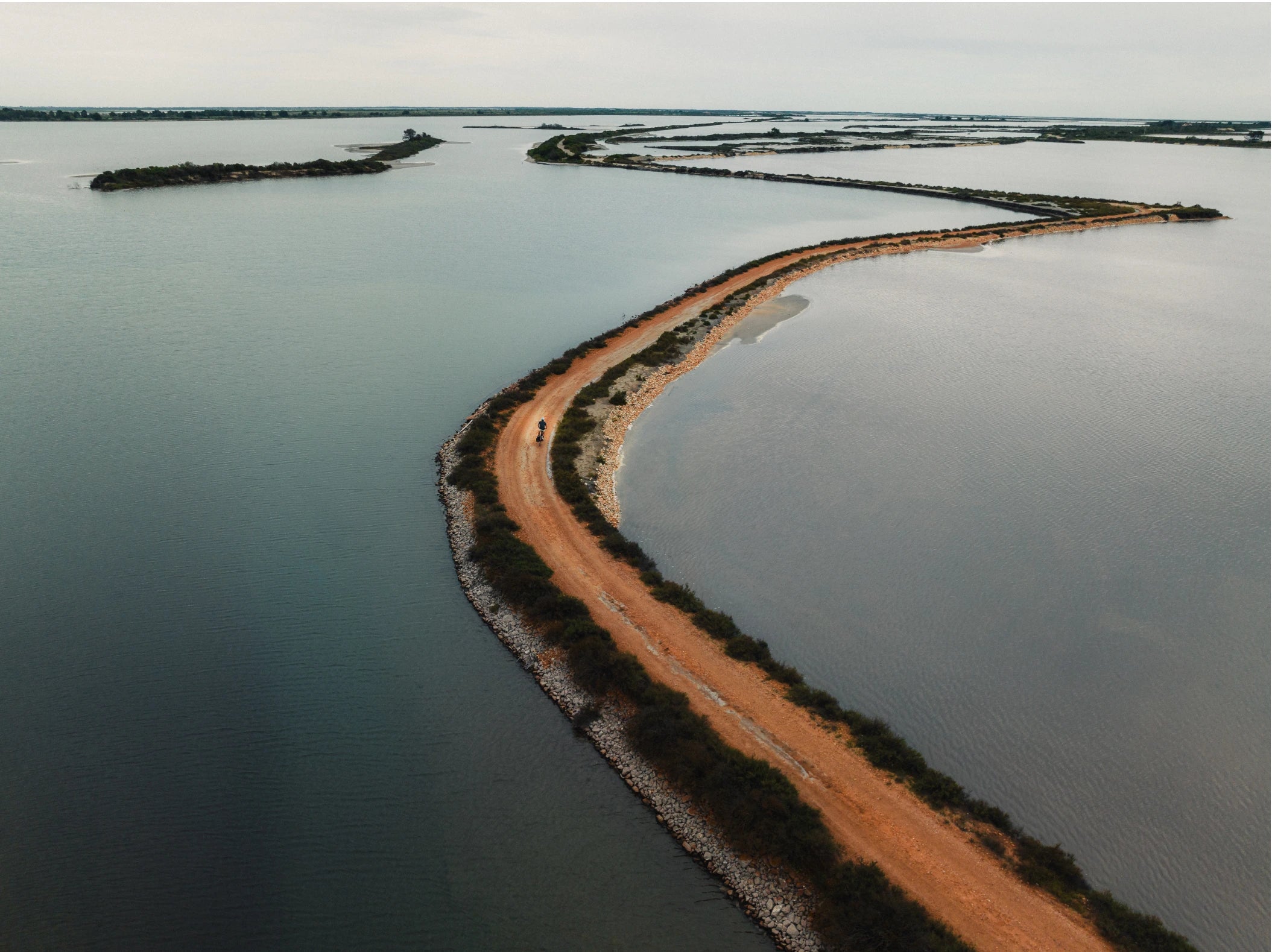 Un homme filmé au drone roule en vélo Bastille au milieux des salins de Camargue