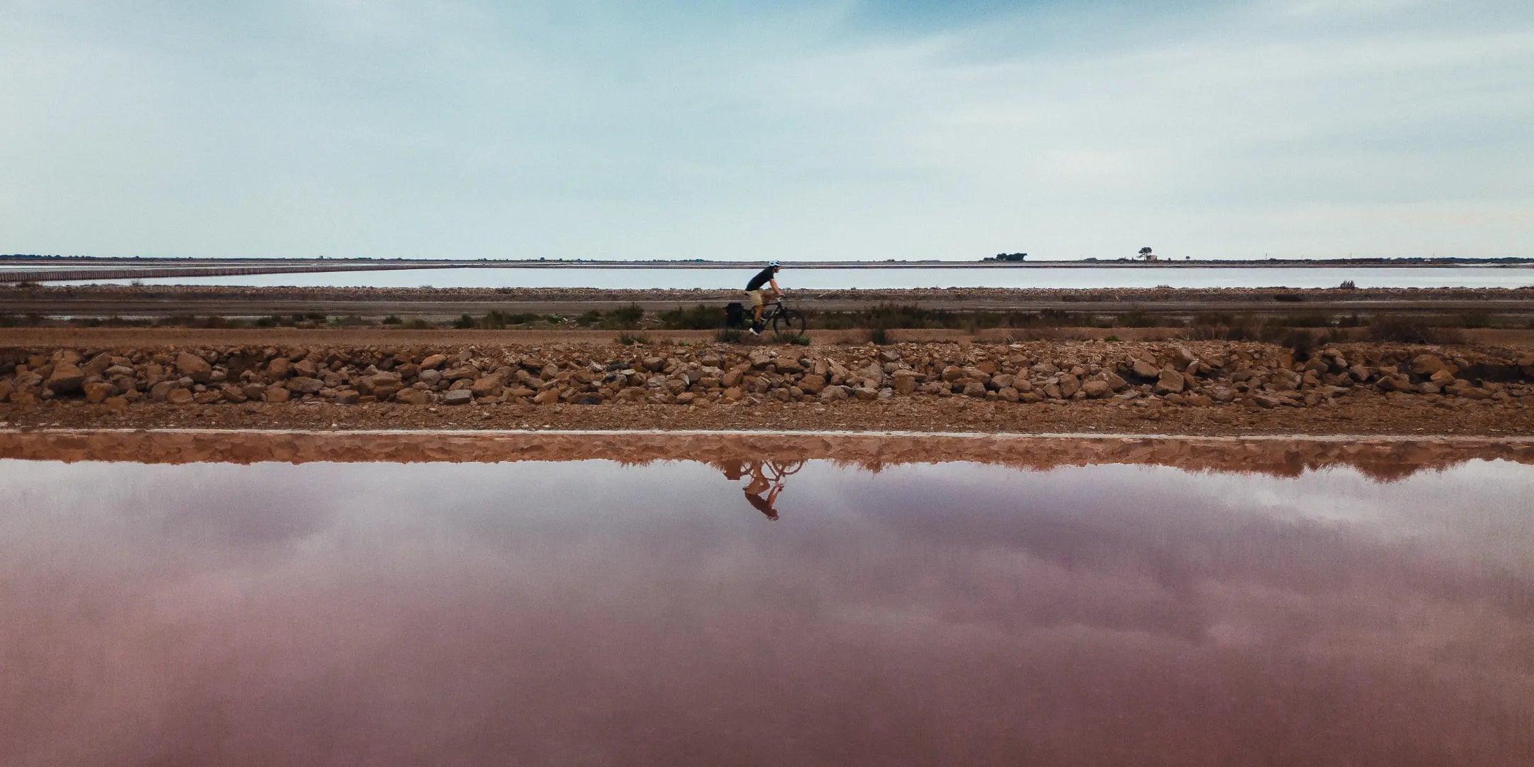 Un homme roule en Bastille équipé de son porte-sacoches au milieu des salins de Camargue