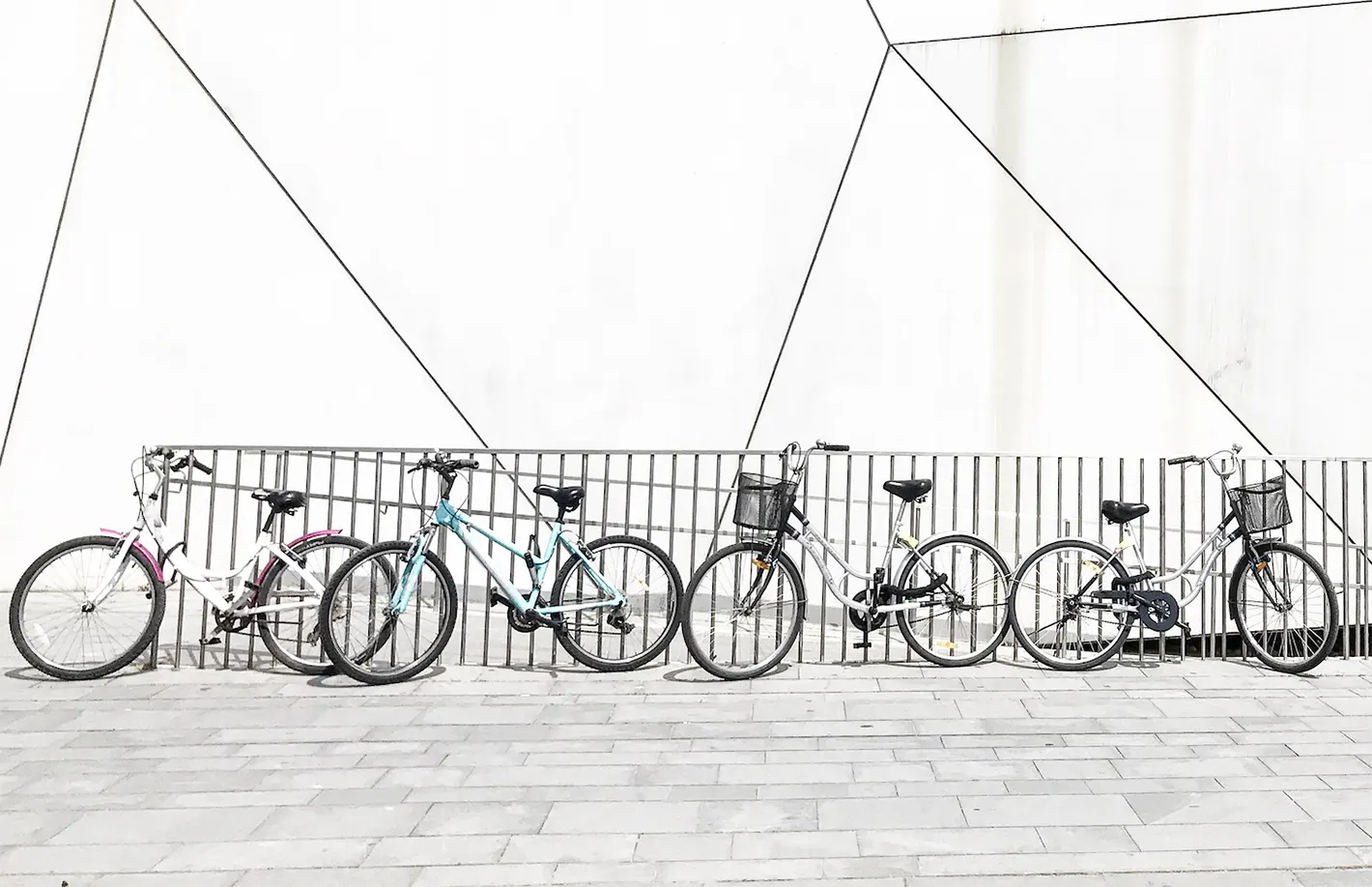 Plusieurs vélos urbains alignés stationnés le long d'une grille