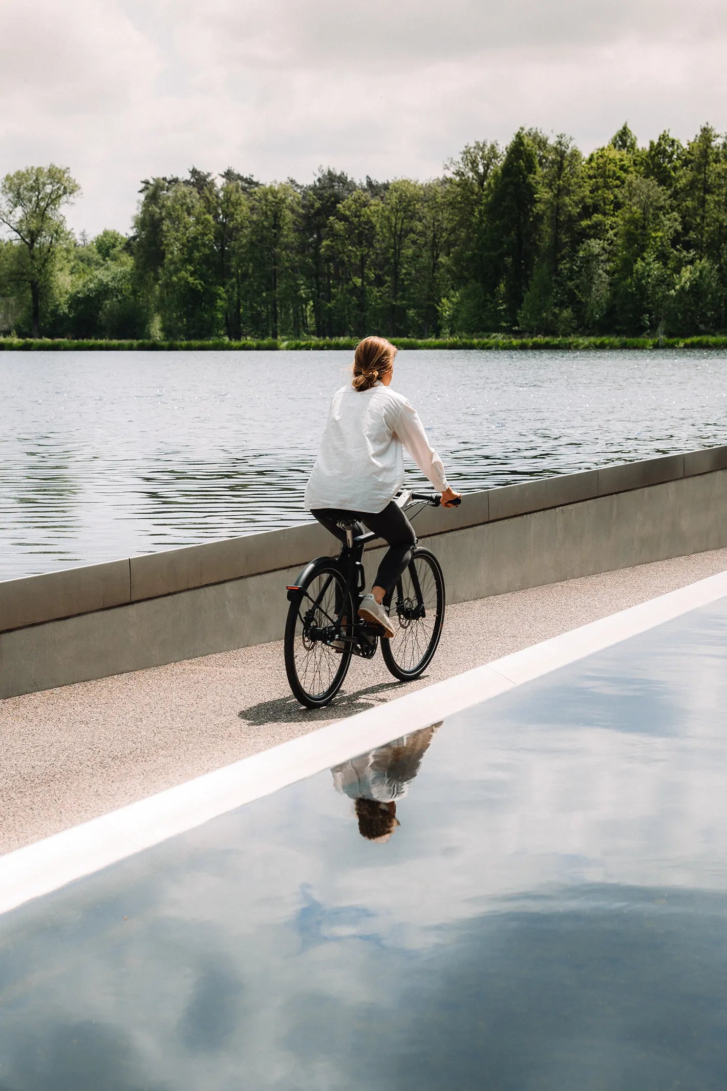 Cycliste sur son vélo Bastille, sereine en traversant un lac sur une piste cyclable.