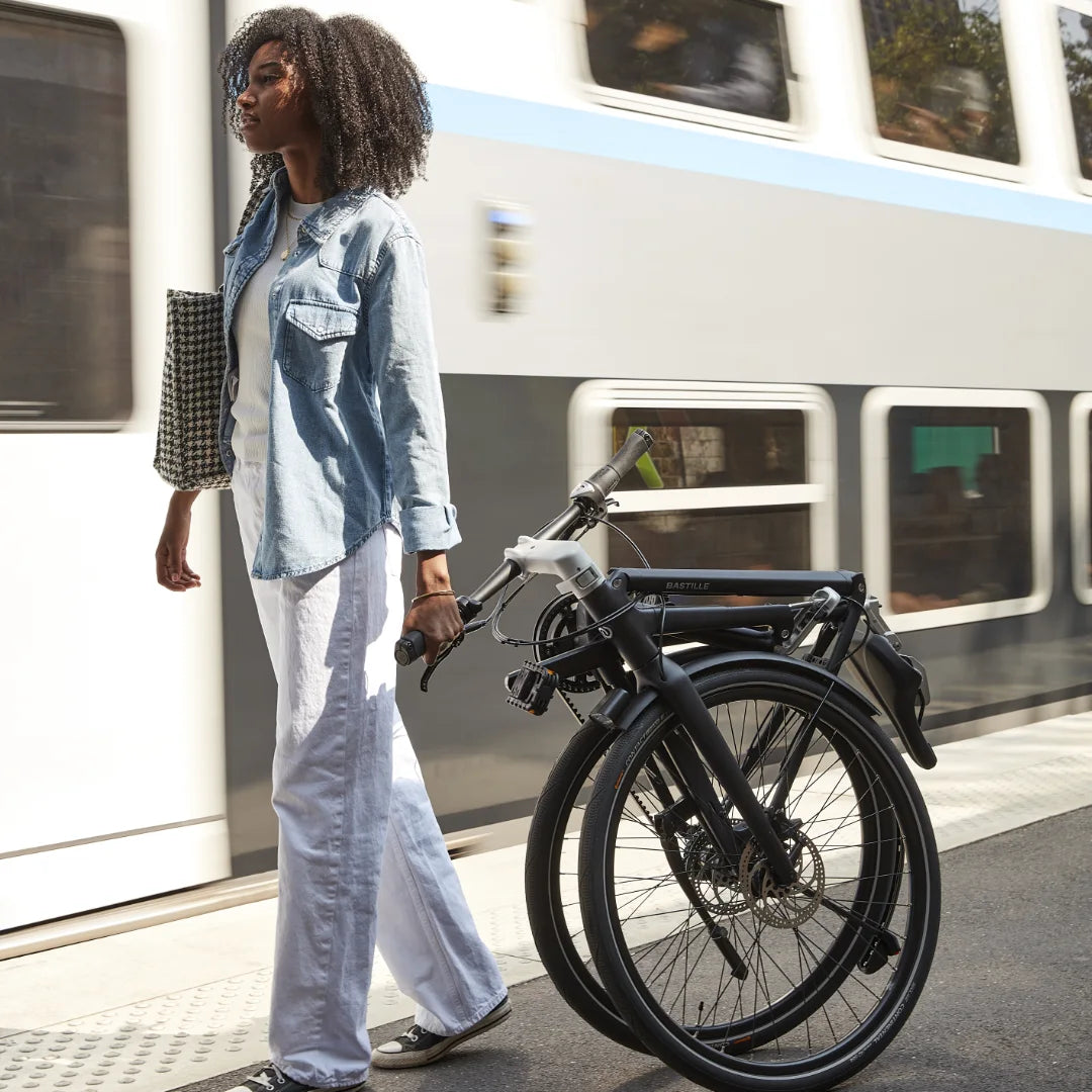 Une femme tire le vélo Bastille plié derrière elle