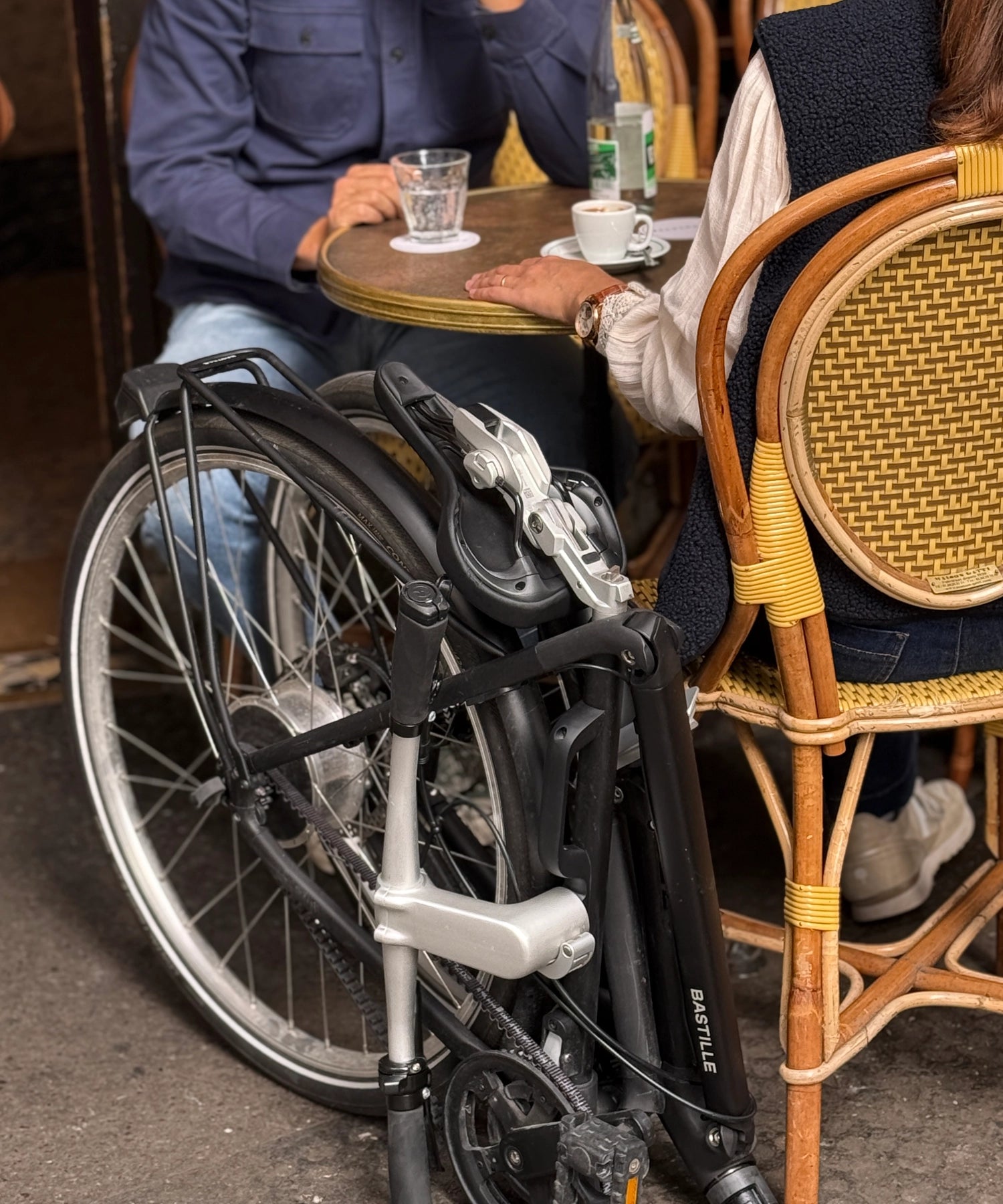 Le Bastille E plié aux pieds d'un couple en terrasse.