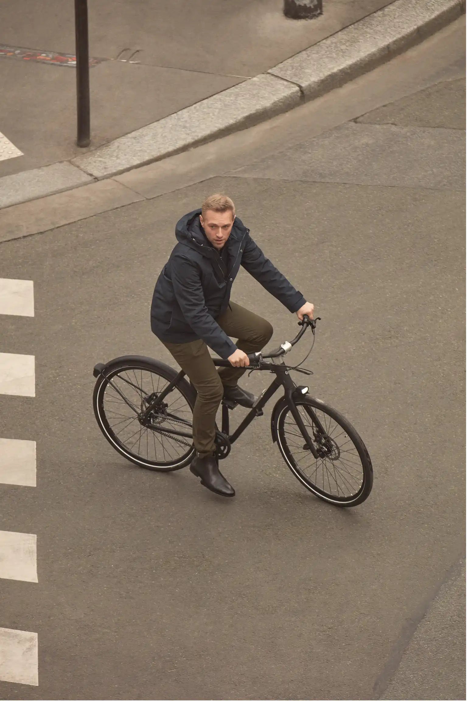 Un homme dans une boulangerie avec son vélo pliant à grandes roues plié devant lui